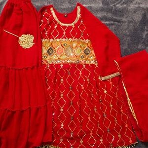 It’s red color sharara suit with duppata and with maang tikka